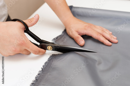a man cuts fabric with scissors on a table close-up