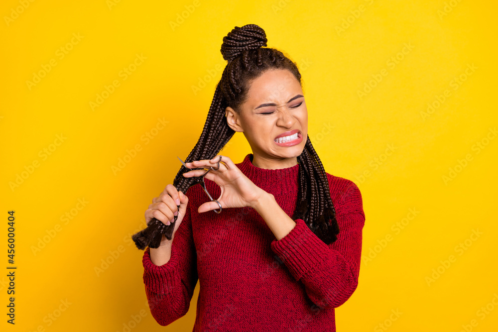 Obraz premium Photo of sad angry dark skin lady wear red pullover cutting braids isolated yellow color background