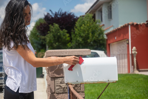 young woman checking old-fashioned mailbox at the front yard of their house. Selective Focus Mailbox.