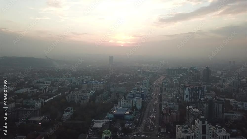 A big city in smog. Ecology of the city of Almaty. View of many roads, cars, people and large mountains. Places smog and fog. People walk the streets. Beautiful buildings with glass Windows. Trees. A big city in smog. Ecology of the city of Almaty. View of many roads, cars, people and large mountains. Places smog and fog. People walk the streets. Beautiful buildings with glass Windows. Trees.