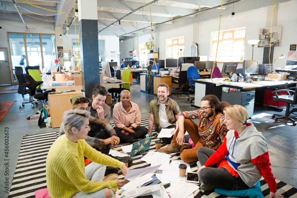 Team sitting on floor, discussing paperwork Team sitting on floor, discussing paperwork