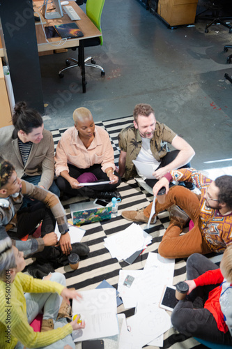 Team sitting on office floor, discussing paperwork