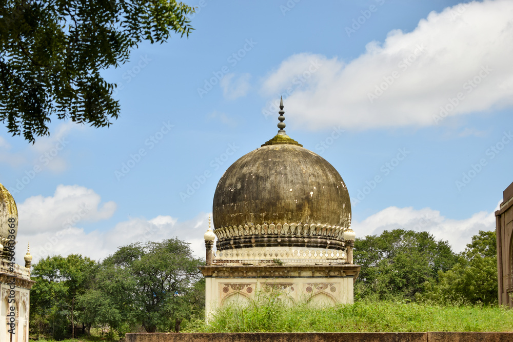 Obraz premium Antique Islamic Architectural Art Pointed Arches Seven Tombs Dome and Blue Sky Green Trees