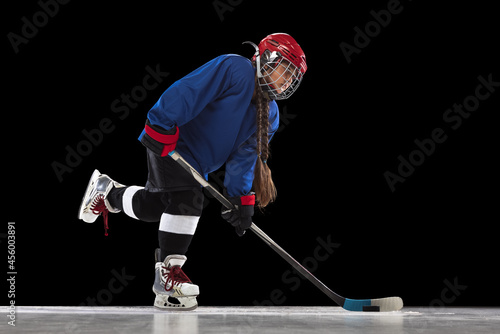 Photography Full-length portrait of child girl, hockey player isolated over black background