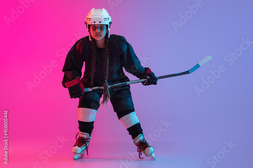 Canvas Print Portrait of child girl - professional hockey player isolated over gradient pink purple background
