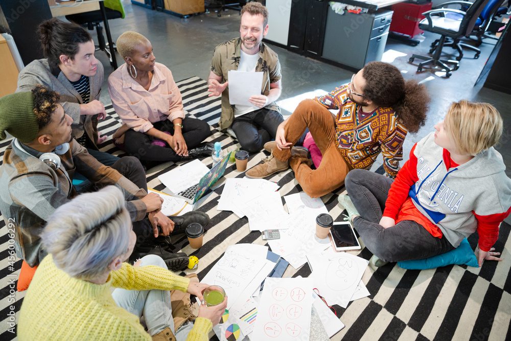Team sitting on floor, discussing paperwork Team sitting on floor, discussing paperwork
