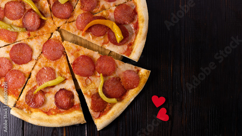 Pepperoni pizza and heart symbol on wood background. Pizza love concept
