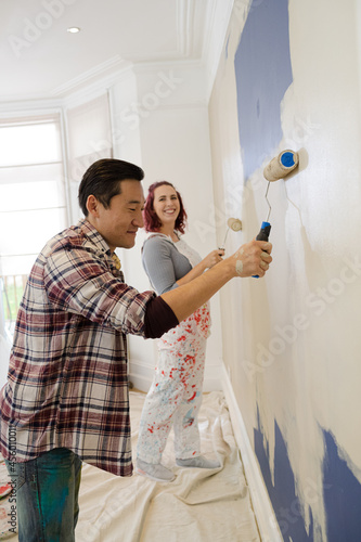 Happy, playful couple with paint rollers painting room