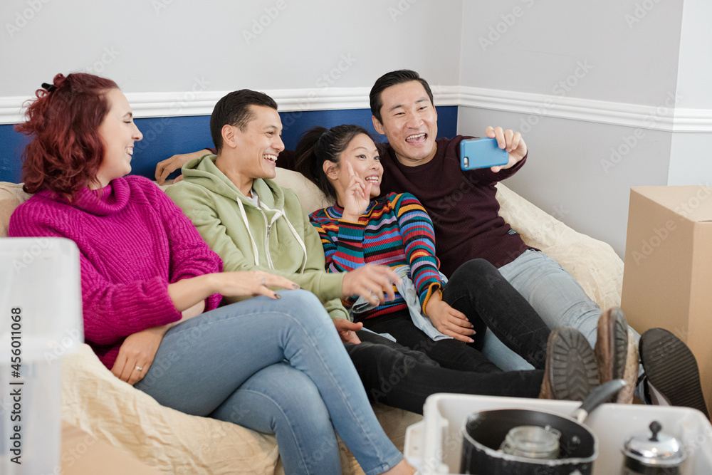 Happy friends taking a break from moving, taking selfie on sofa Happy friends taking a break from moving, taking selfie on sofa