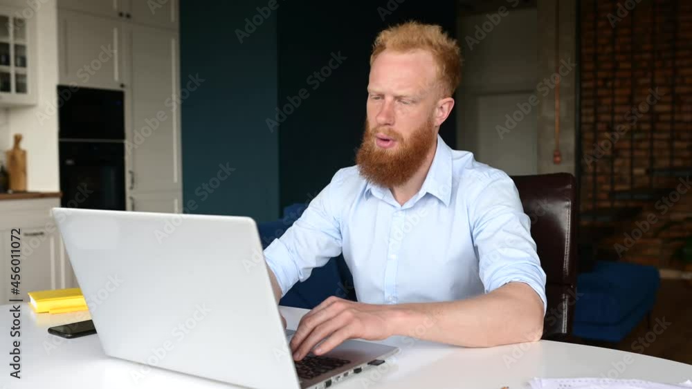 Tired red haired businessman massaging back of the neck, feels muscle tense, young bearded caucasian freelancer take a break from work with a laptop sitting in the home office Tired red haired businessman massaging back of the neck, feels muscle tense, young bearded caucasian freelancer take a break from work with a laptop sitting in the home office