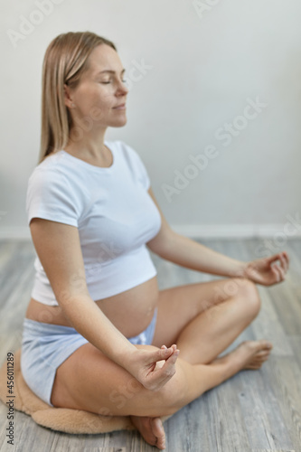 Close-up view of young pregnant woman doing morning yoga exercise