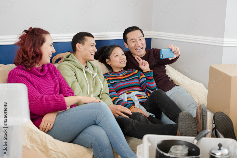 Happy friends taking a break from moving, taking selfie on sofa Happy friends taking a break from moving, taking selfie on sofa