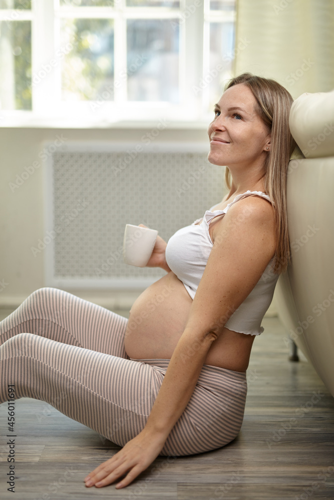 Pregnant woman caressing her belly at home. Pregnant woman caressing her belly at home.