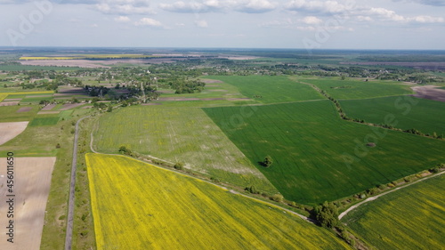 Colorful farm fields around a small village, aerial view. © Oleksii