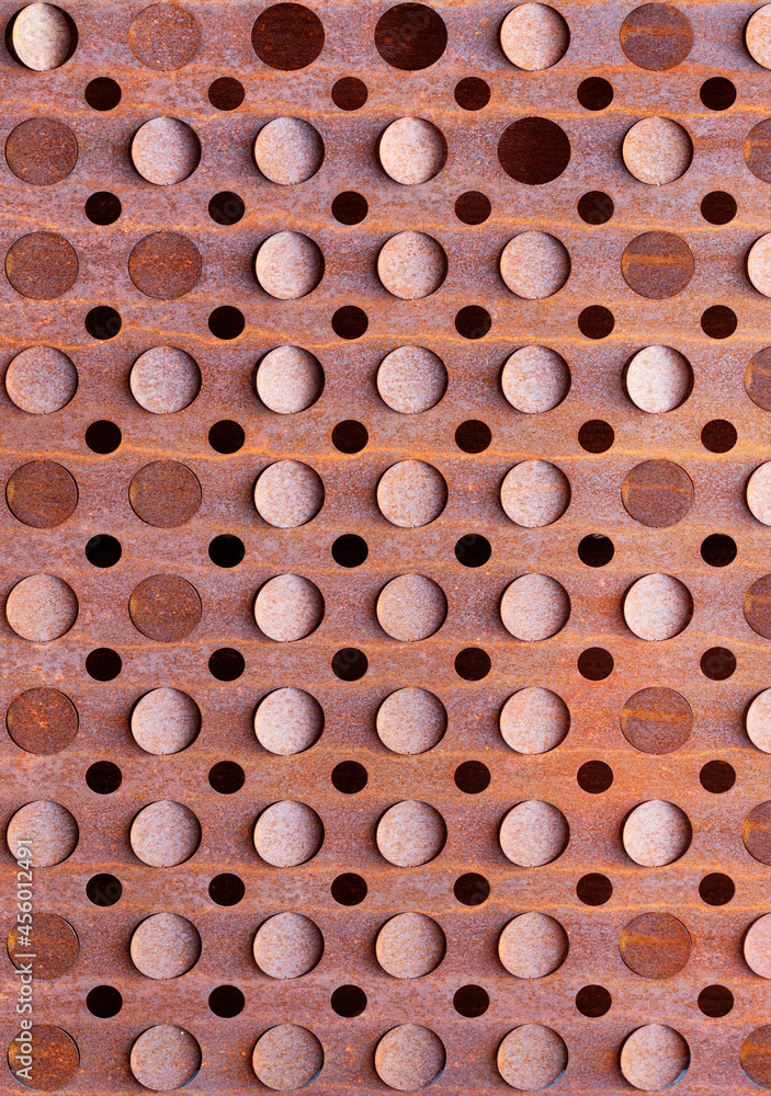 Round holes on a rusty old sheet of metal texture. Vertical image.