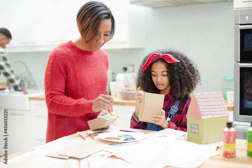 Mother and daughter painting cardboard houses Mother and daughter painting cardboard houses