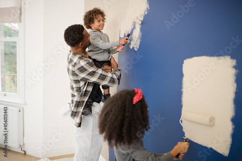 Φωτογραφία Happy father and children with paint rollers painting room