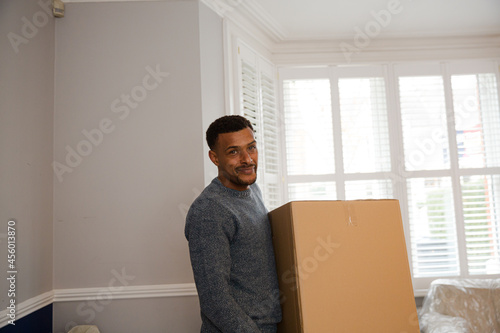 Portrait happy man carrying moving box in corridor