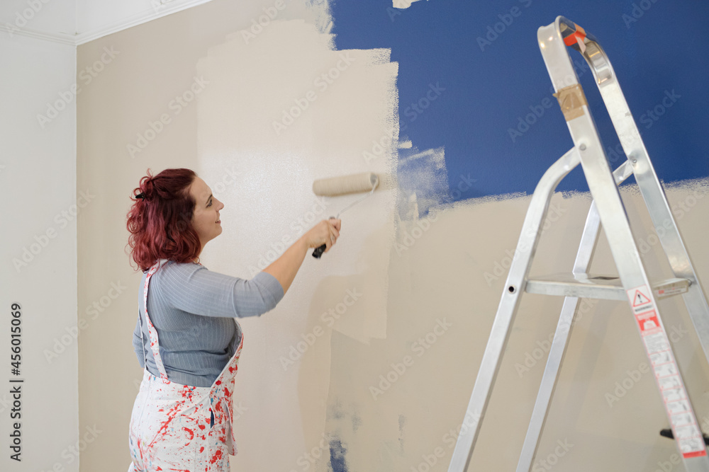 Woman in overalls painting wall