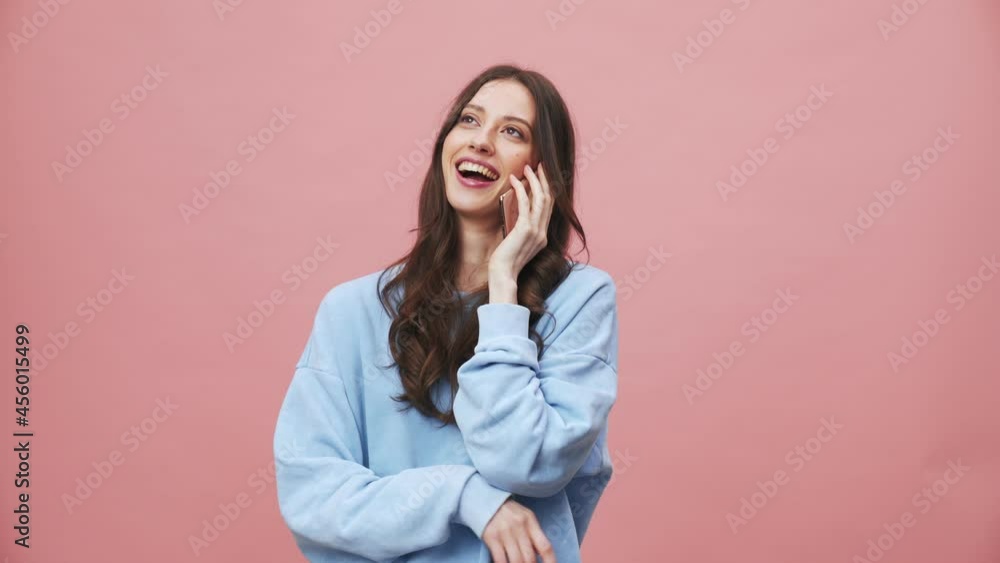A happy brunette woman talking on her mobile isolated over pink background in the studio A happy brunette woman talking on her mobile isolated over pink background in the studio
