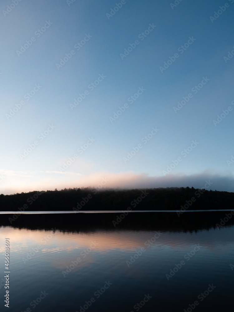 Dawn over a lake and a forested hillside in New Hampshire