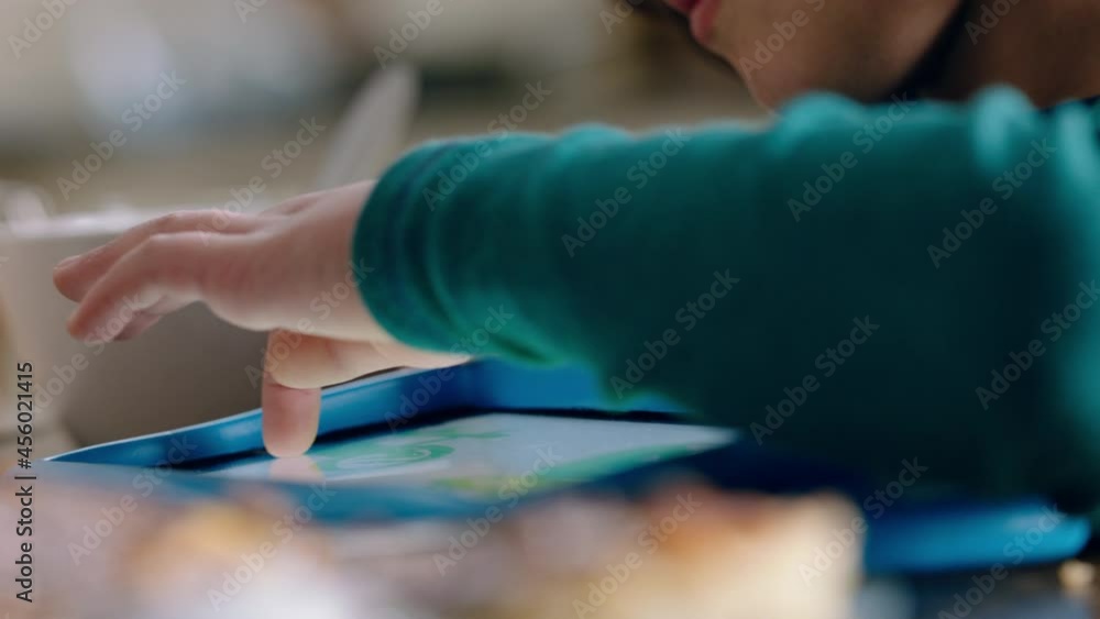 child using digital tablet computer little boy playing games having fun learning on touchscreen technology at home at breakfast