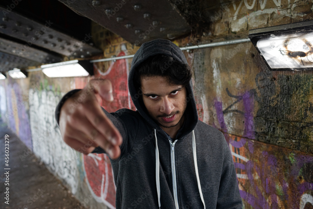Portrait menacing young man gesturing finger gun in urban tunnel