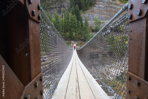 Fototapeta Naklejka Na Ścianę i Meble -  Man walking on a swinging bridge