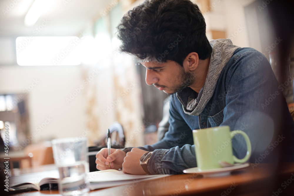 Focused young male college student studying in cafe Focused young male college student studying in cafe