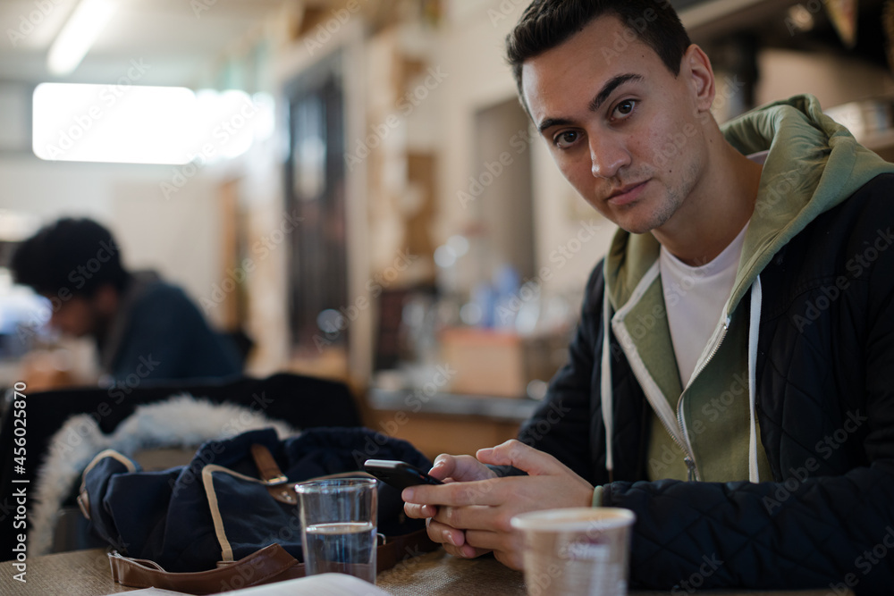 Portrait confident young male college student using smart phone in cafe Portrait confident young male college student using smart phone in cafe