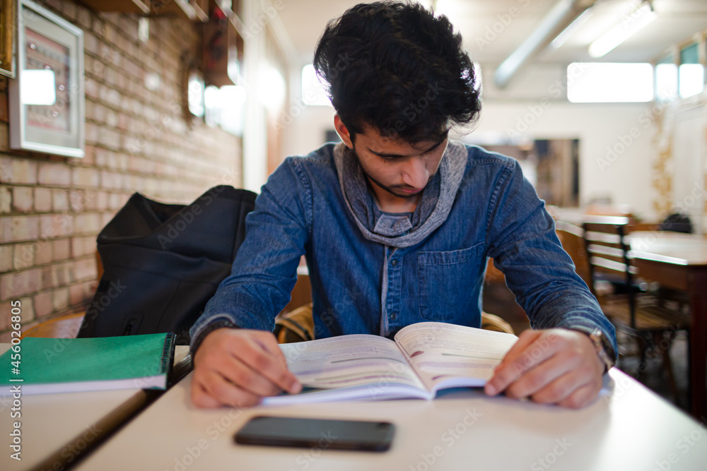 Focused young male college student studying in cafe Focused young male college student studying in cafe