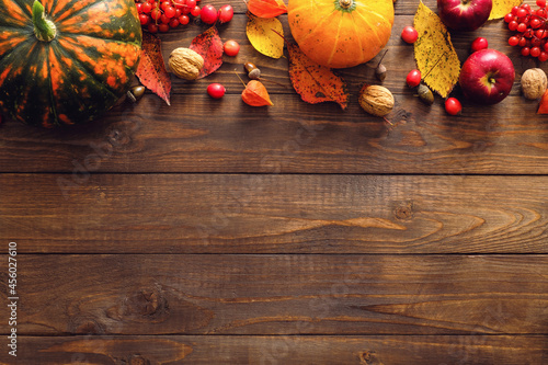Harvest or Thanksgiving background with ripe orange pumpkins  fallen leaves  dry flowers on rustic wooden table. Flat lay  top view  copy space.