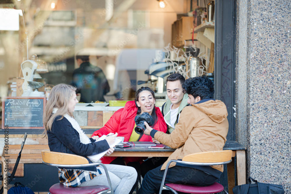 Young adult college students with digital camera at sidewalk cafe