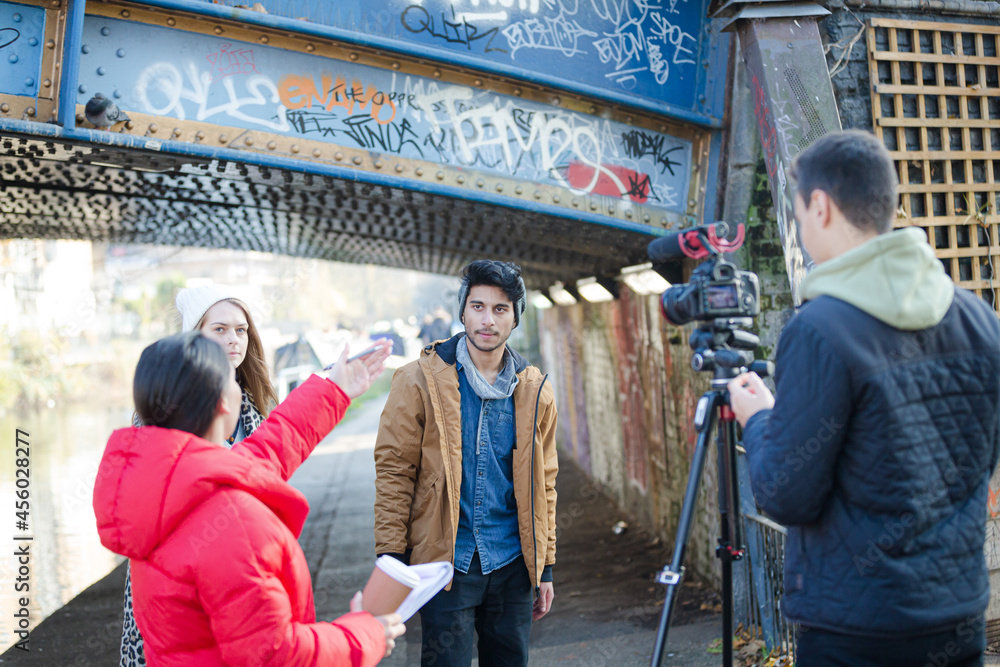 Fototapeta premium Young adults vlogging under urban bridge