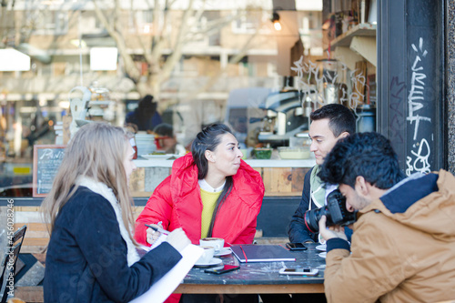 Young adult friends talking at sidewalk cafe