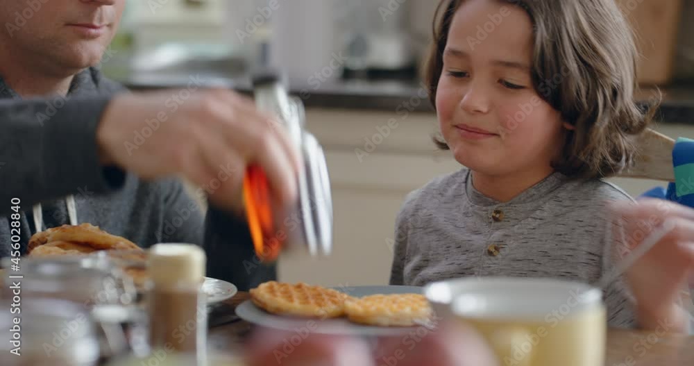 happy little boy eating fresh waffles for breakfast enjoying delicious homemade treat with father helping his son in kitchen at home 4k happy little boy eating fresh waffles for breakfast enjoying delicious homemade treat with father helping his son in kitchen at home 4k