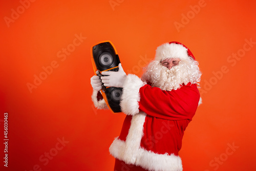 Funny Santa Claus as a DJ with a retro tape recorder on an orange background. Culture and Religion.