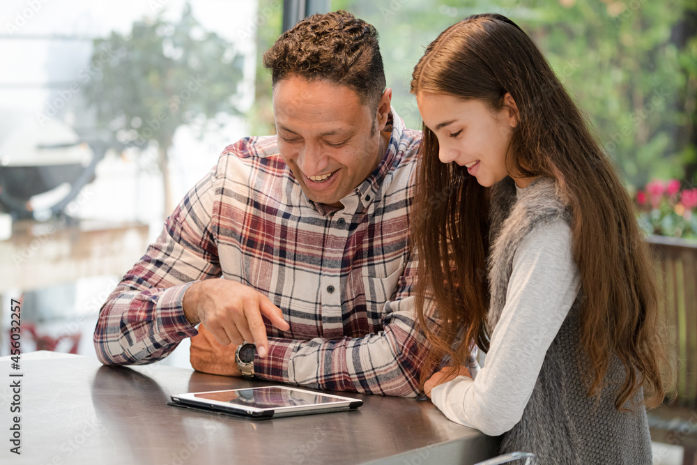 Smiling father and daughter using digital tablet at kitchen counter Smiling father and daughter using digital tablet at kitchen counter