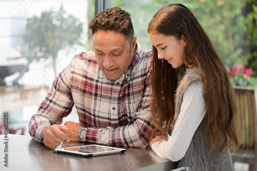 Smiling father and daughter using digital tablet at kitchen counter
