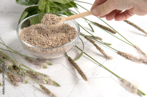 A woman's hand with a wooden spoon with psyllium seed husk, a useful superfood. The concept of plant fiber