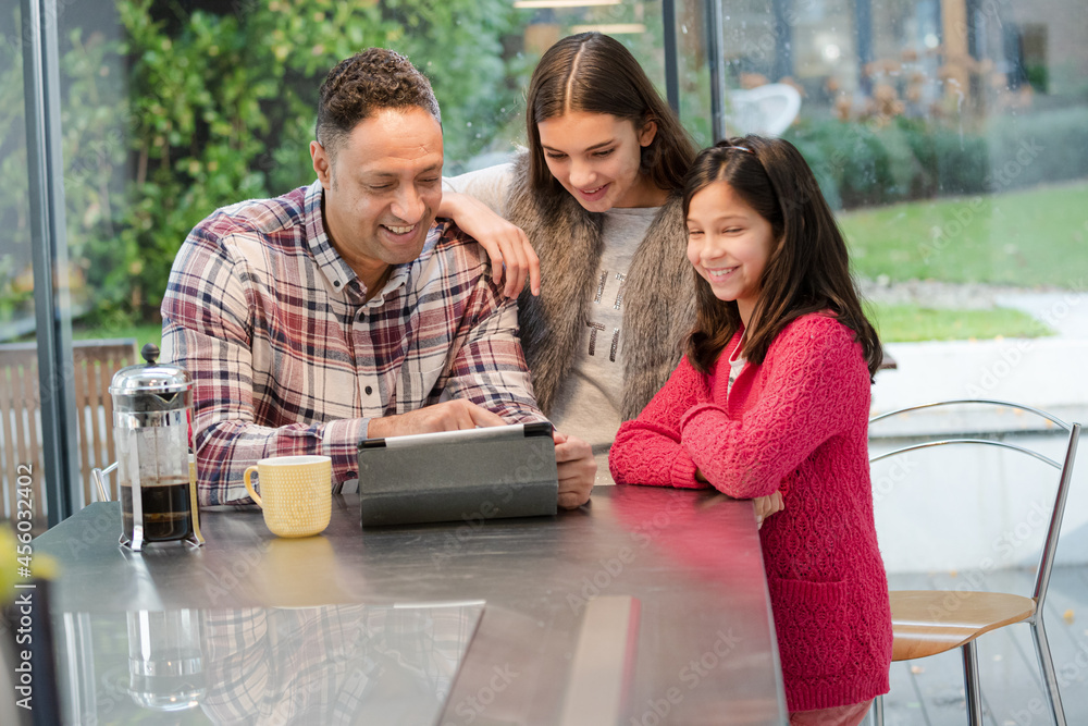 Father and daughters using digital tablet in morning kitchen Father and daughters using digital tablet in morning kitchen