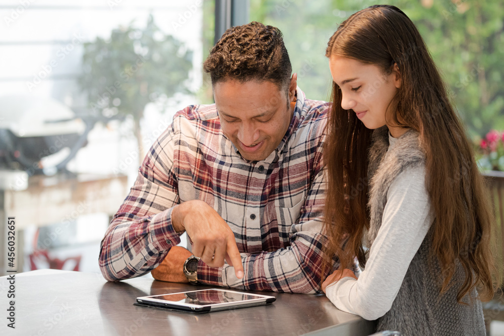 Smiling father and daughter using digital tablet at kitchen counter Smiling father and daughter using digital tablet at kitchen counter