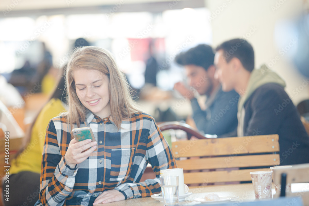 Smiling young woman using smart phone in cafe Smiling young woman using smart phone in cafe