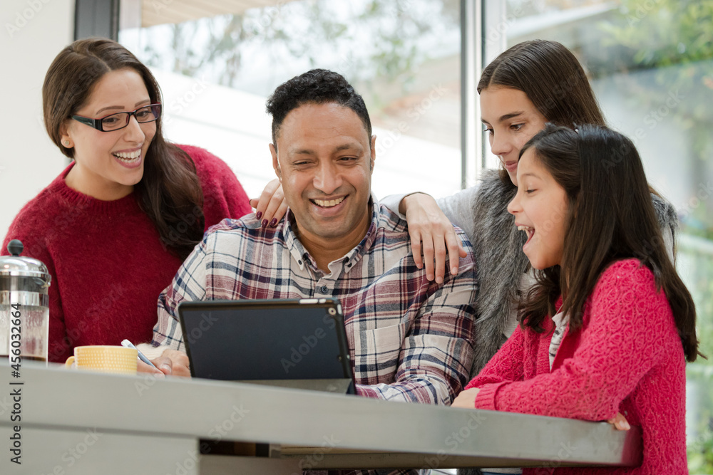 Happy family using digital tablet at kitchen table Happy family using digital tablet at kitchen table