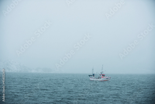 fishing boat in foggy ocean in northern norway