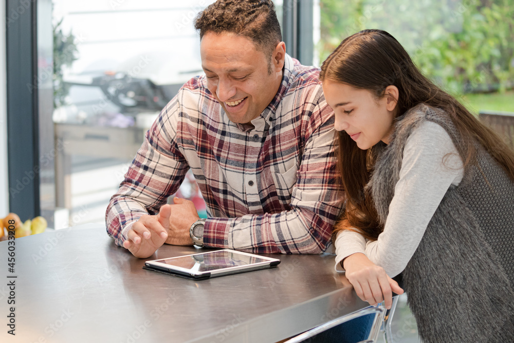 Smiling father and daughter using digital tablet at kitchen counter Smiling father and daughter using digital tablet at kitchen counter