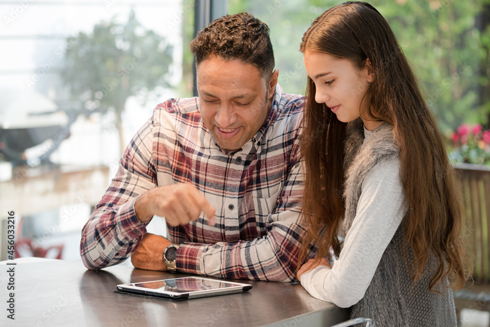 Smiling father and daughter using digital tablet at kitchen counter Smiling father and daughter using digital tablet at kitchen counter