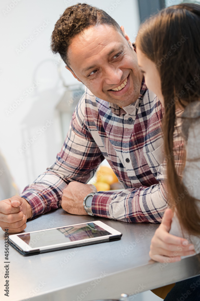 Smiling father and daughter using digital tablet at kitchen counter Smiling father and daughter using digital tablet at kitchen counter