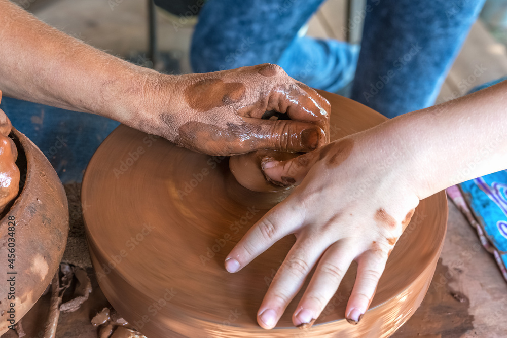 Festival of folk crafts. Master class in pottery. A potter teaches a child to make dishes from red clay.