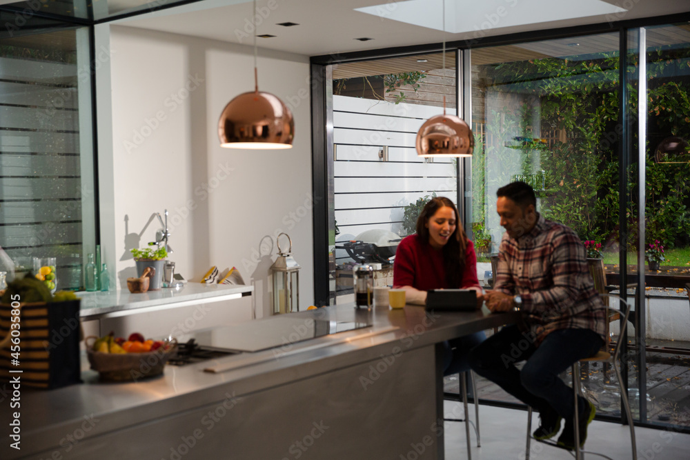 Couple financial planning at digital tablet in kitchen Couple financial planning at digital tablet in kitchen